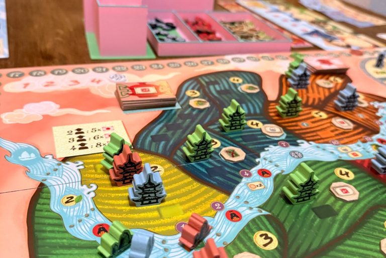 Das Brettspiel zeigt eine detaillierte Landschaft mit farbigen Spielfiguren und Ressourcen.