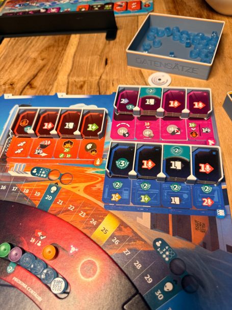 Brettspiel mit bunten Karten, Spielsteinen und verschiedenen Spielbrettabschnitten.