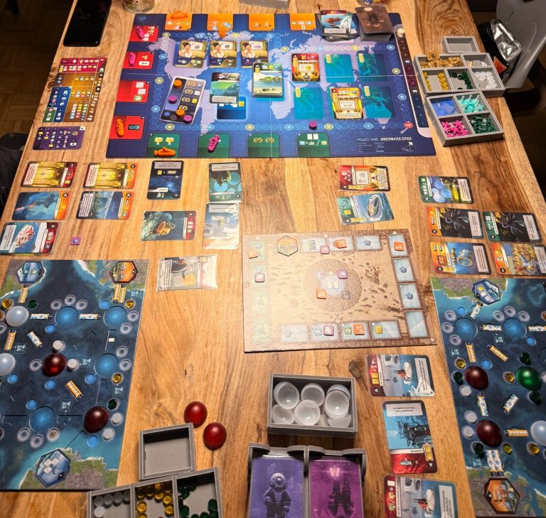 Brettspiel-Setup mit mehreren Spielbereichen und Karten auf einem Tisch.