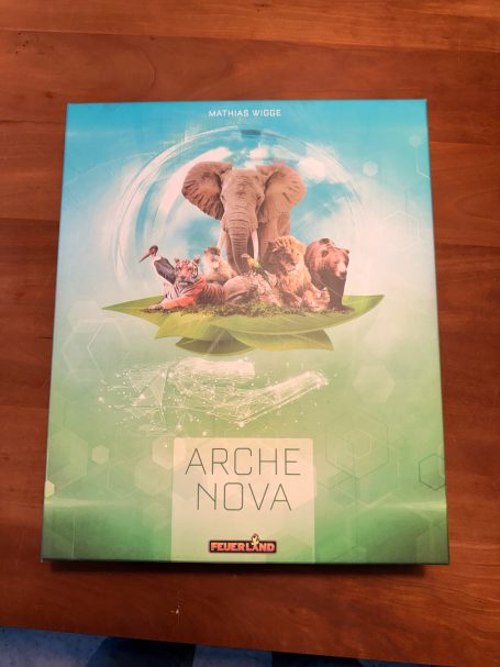 Cover des Spiels "Arche Nova" mit einem Elefanten und verschiedenen Tieren auf einer grünen Fläche.