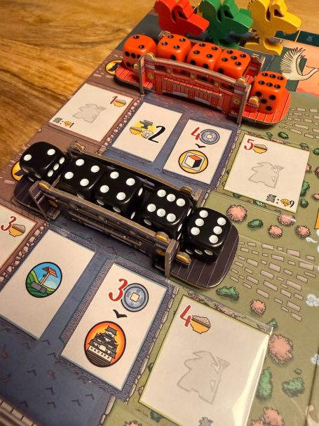 Doppelte Würfel in verschiedenen Farben auf einem Brettspiel mit Aktionsfeldern.