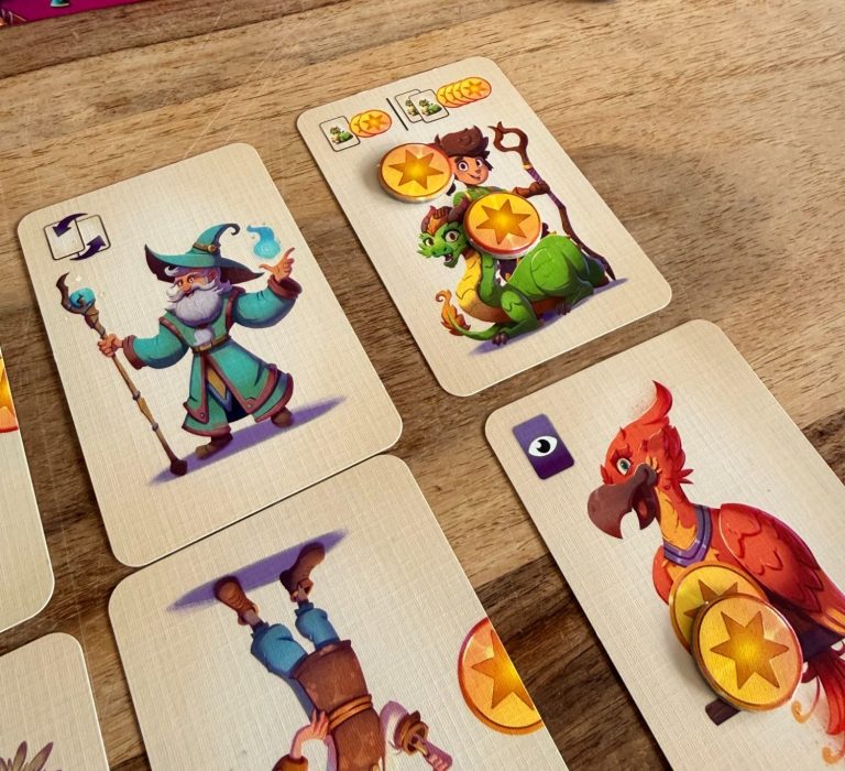 Karten mit einem Zauberer, einem Drachen und einem roten Vogel, versehen mit goldenen Münzen.