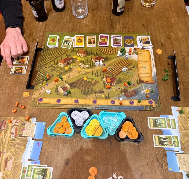 Brettspiel auf einem Tisch mit Karten, Würfeln und verschiedenen Spielsteinen.