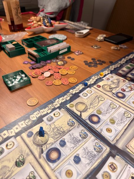 Tisch mit Brettspielen, Spielkarten, Spielsteinen und Spielgeld verteilt.