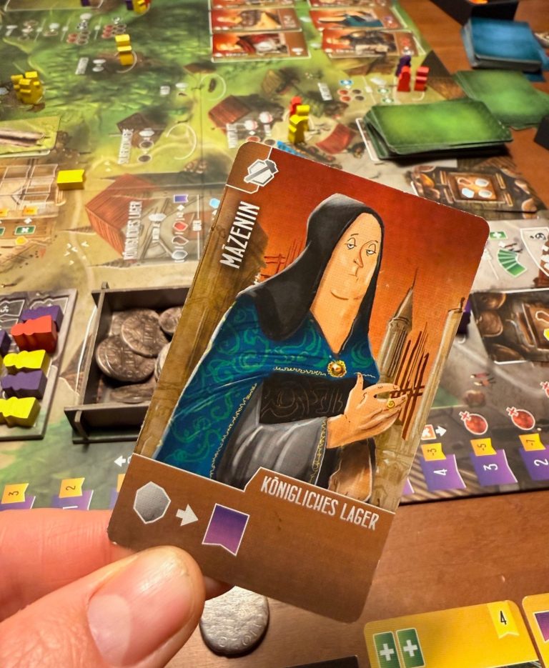 Spielkarte mit einer Nonne, die Bücher hält, in einem Brettspiel-Setup.
