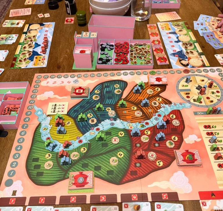 Brettspiel-Setup mit mehreren Spielbereichen und Karten auf einem Tisch.