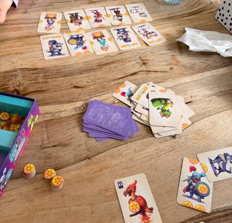 Ein Tisch mit Spielkarten, Figuren und Spielmarken in bunten Farben.