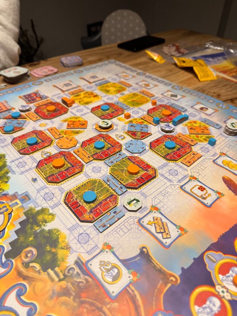 Das Bild zeigt ein Brettspiel mit bunten Spielfeldern und Spielsteinen auf einem Tisch.