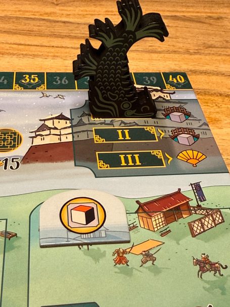 Grüner Spielstein in Form eines Drachen auf einem Brettspiel mit verschiedenen Spielbereichen.