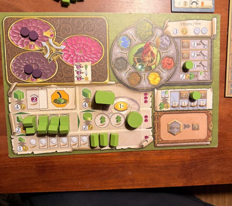 Brettspiel mit bunten Komponenten und verschiedenen Spielfeldern auf einem Tisch.