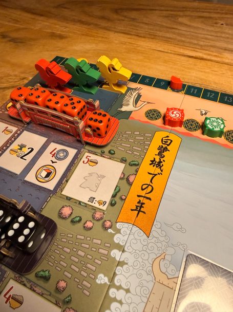 Brettspiel mit bunten Spielsteinen und Karten auf einem Holztisch.