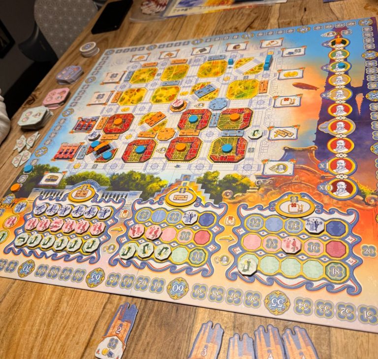 Brettspiel mit buntem Spielbrett, Karten und Spielfiguren auf einem Holztisch.