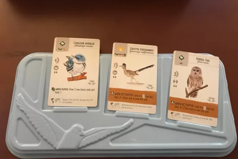 Brettspiel mit Spielkarten, Ressourcen und Spielfiguren auf einem grünen Spielbrett.