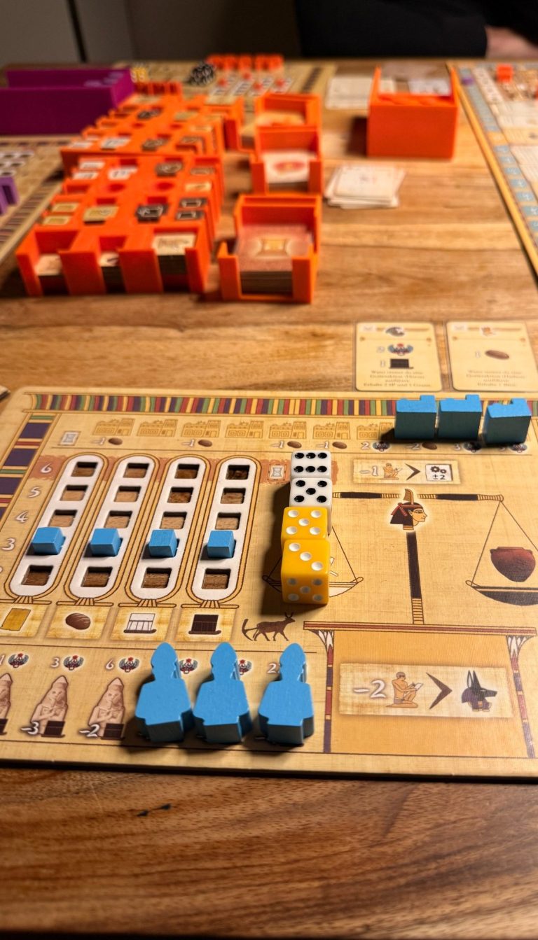 Brettspiel mit bunten Spielfiguren, Würfeln und Spielkarten auf einem Tisch.