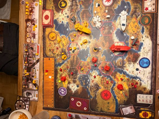 Brettspiel mit farbigen Spielsteinen auf einer detaillierten Landschaftskarte.