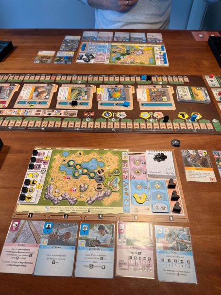 Ein Tisch mit mehreren Brettspielen, Karten und Spielfiguren.
