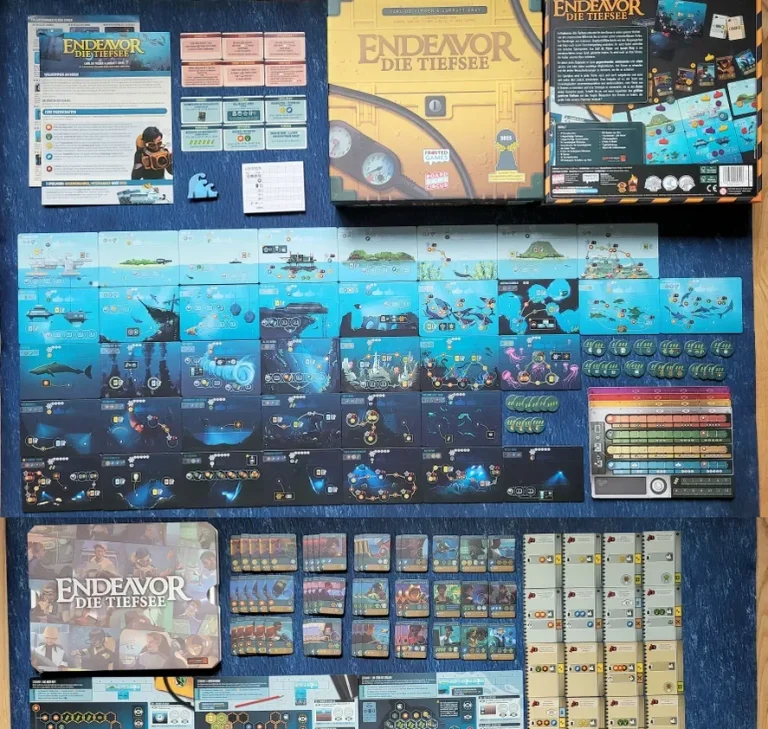 Viel Spielmaterial bei Endeavor - die Tiefsee Brettspiel-Setup mit Spielbrett, Karten, Tokens und Anleitung auf einem blauen Untergrund.