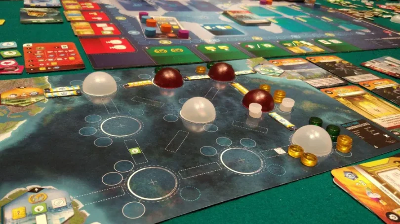 Brettspiel mit verschiedenen Ressourcen und Spielfiguren auf einem Tisch.
