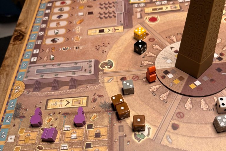 Brettspiel mit bunte Spielfiguren und einem hohen Würfel in der Mitte des Spielplans.