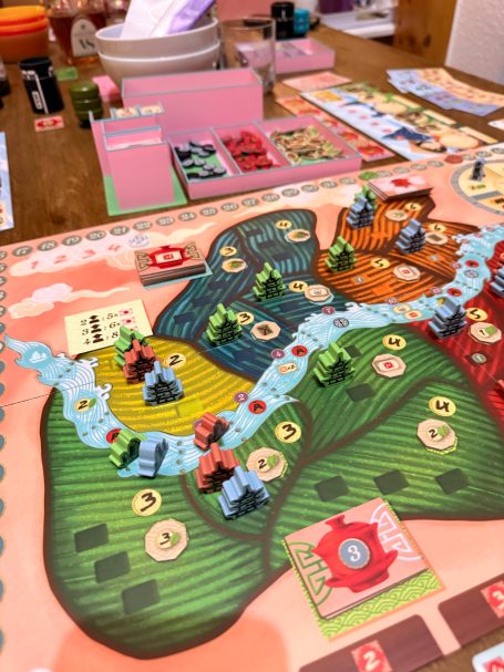 Brettspiel mit bunten Spielfiguren und verschiedenen Regionen auf dem Spielbrett.