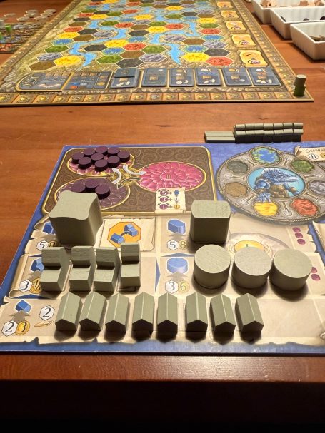 Spielbrett mit verschiedenen Spielsteinen in geometrischen Formen auf Holzuntergrund.