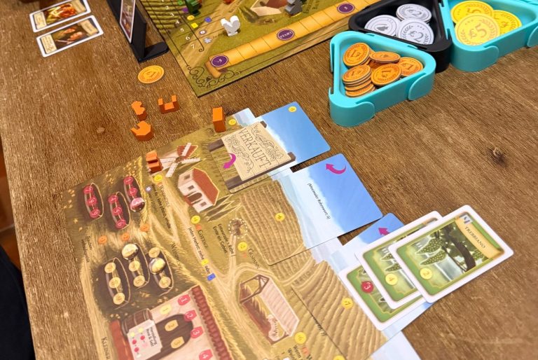 Spielelemente auf einem Tisch: Karten, Tokens und ein Spielbrett mit Landwirtschaftsthema.