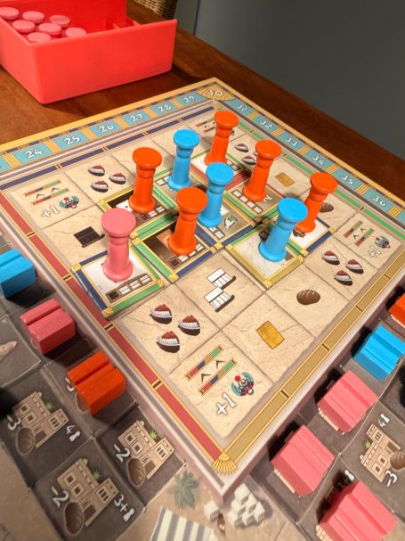 Brettspiel mit bunten Figuren und Spielsteinen auf einem Spielebrett.
