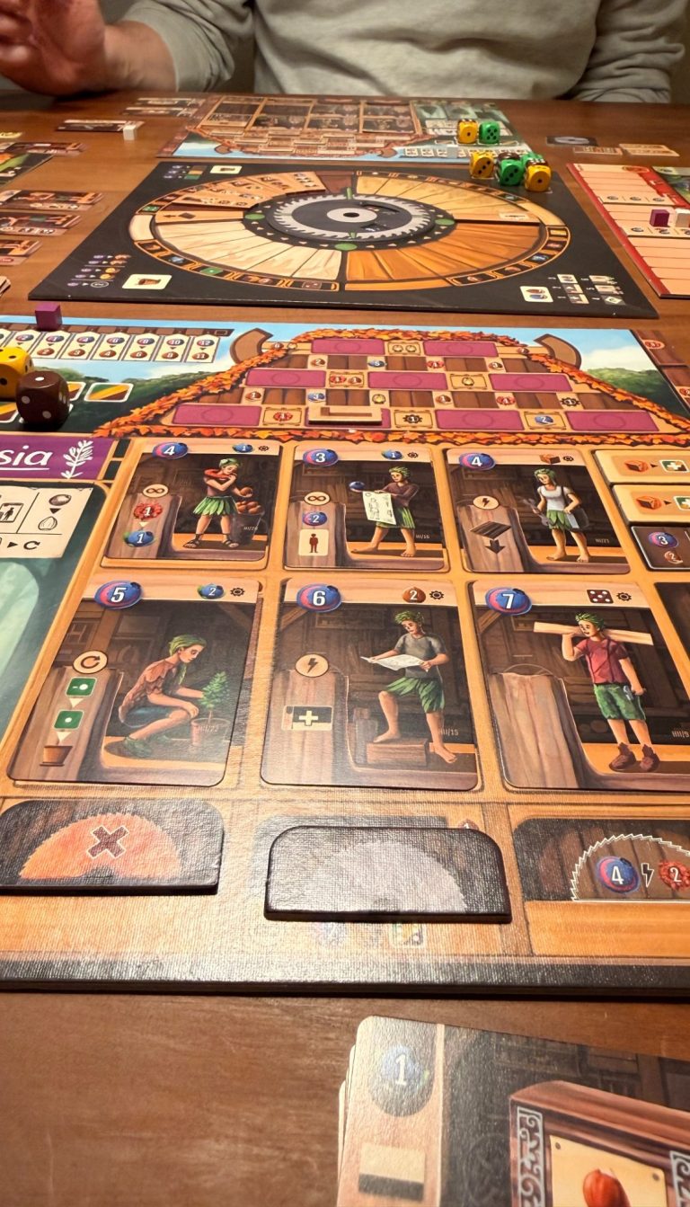 Spieler hält zwei Aktionskarten mit Obst, Nüssen und einem Segelboot, umgeben von Spielbrett.