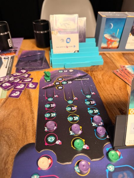 Brettspiel mit bunten Spielsteinen und Karten auf einem Holztisch.