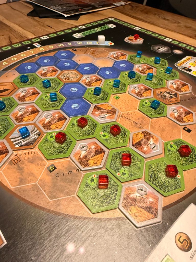 Brettspiel mit bunten Spielfiguren, Ressourcen und Siegpunkt-Übersicht.