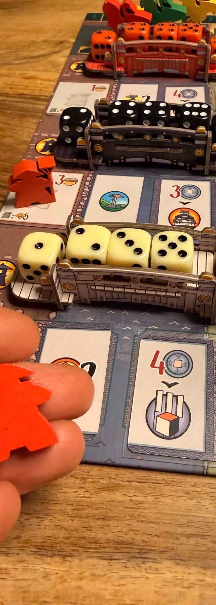 Ein Spielbrett mit Würfeln, Spielsteinen und verschiedenen Spielfeldfeldern.