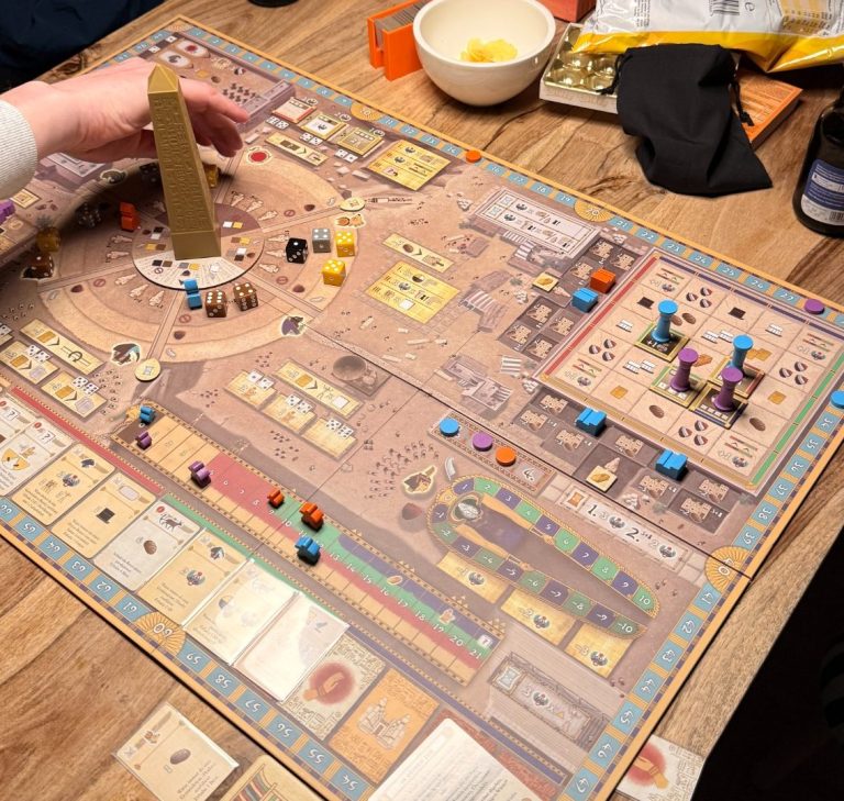 Ein Tisch mit einem Brettspiel und bunten Spielsteinen in verschiedenen Bereichen.
