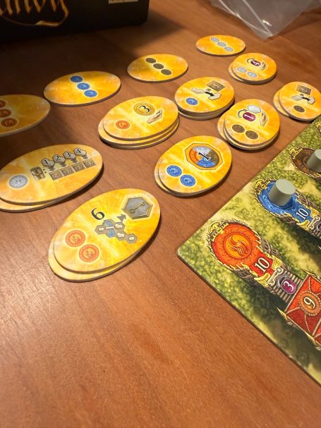 Bunte Spielsteine und Karten liegen auf einem Tisch mit Holzoberfläche.