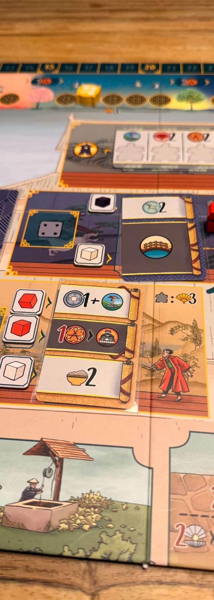 Brettspiel mit verschiedenen Karten, Würfeln und Spielfiguren auf einem Tisch.