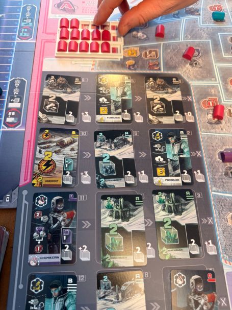Eine Spielszene mit Karten und Spielfiguren auf einem Brettspieltableau.