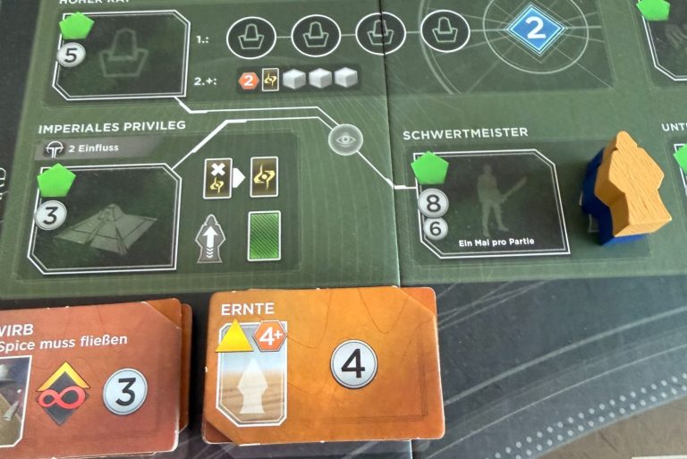 Brettspiel mit Spielkarten, Ressourcen und Spielfiguren auf einem grünen Spielbrett.