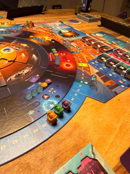 Brettspiel mit bunten Spielfiguren und verschiedenen Stationen auf einem detaillierten Spielbrett.