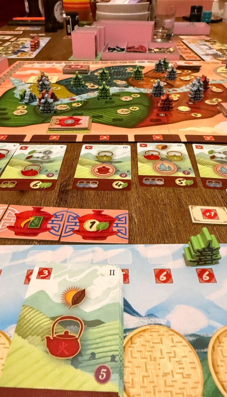 Brettspiel mit Landschaft, Ressourcen und Spielkarten auf einem Tisch.