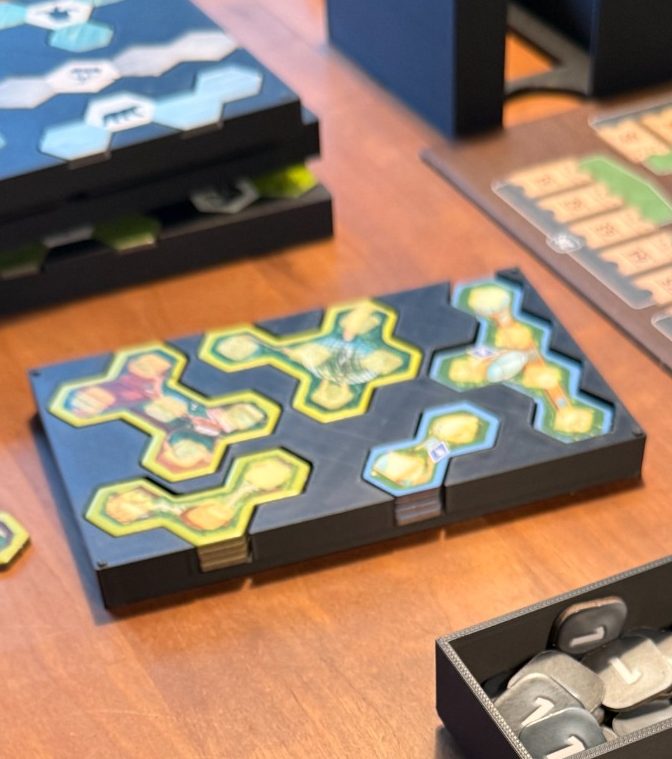 Brettspiel mit bunten Hexagon-Karten auf einem Holztisch angeordnet.