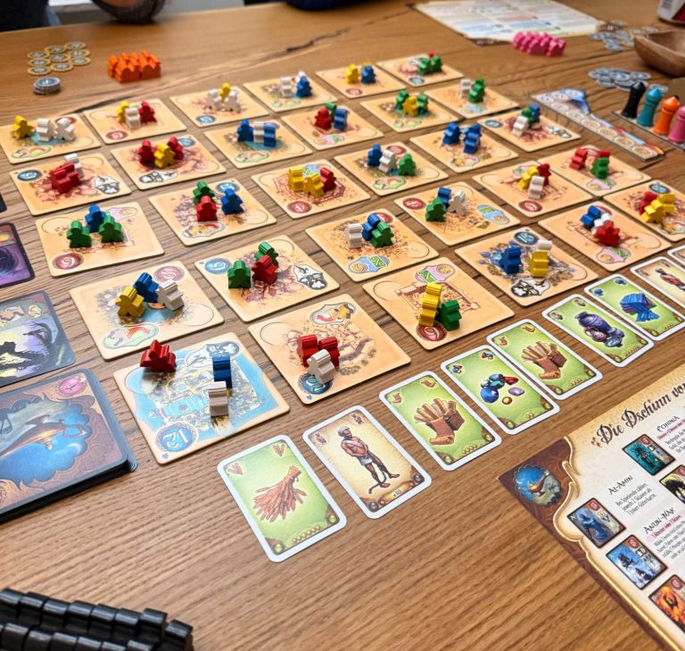 Brettspiel mit bunten Spielfiguren und Karten auf einem Tisch.